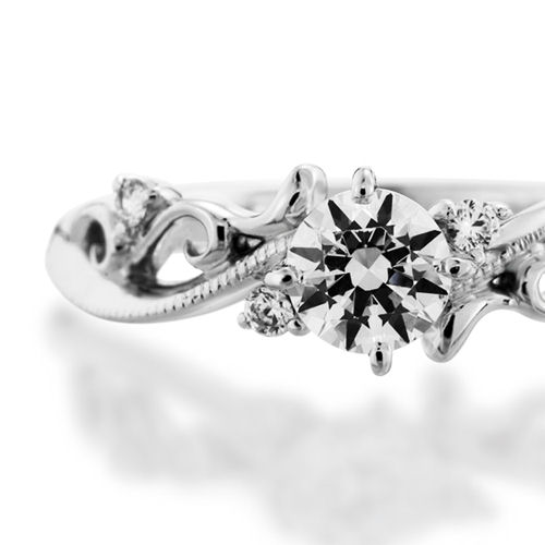 婚約指輪:唐草のような優美な模様のS字ラインにミル打ちを施しメレダイヤを添えたデザイン